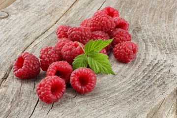ripe raspberries with green leaf on old wooden table