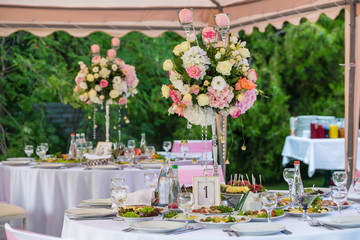 Served round banquet table outdoor in marquee decorated pink flowers and silk