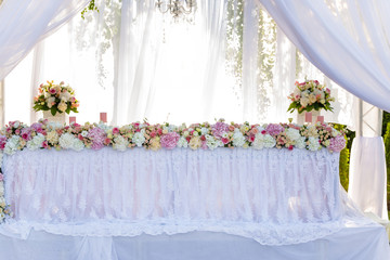 Served wedding banquet table in the garden decorated white lace, pink flowers and silk. newlyweds table