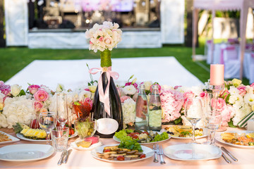 Served round banquet table outdoor in marquee decorated pink flowers and silk