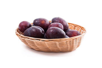 Yellow wooden basket with ripe plums isolated on a white background..