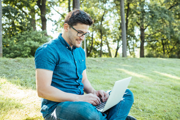 Obraz premium Man with laptop sitting outdoors in nature