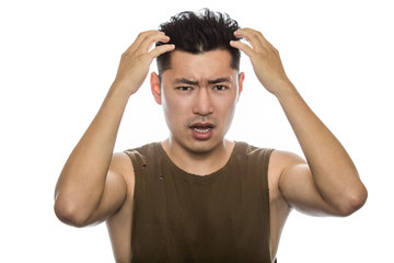 Athletic Asian male with trendy torn sleeveless shirt on a white background.  He is displaying...