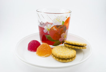 A glass of juice with biscuits and marmalade