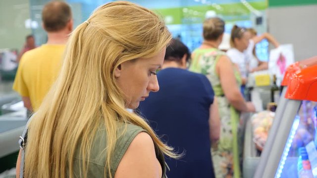 The queue of people standing at the checkout in the supermarket. 4k, slow motion