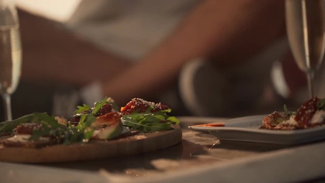 extreme closeup people eating nice food from wooden tray drinking sparkling wine sitting on floor in morning time