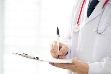 Doctor with a stethoscope and taking notes with bright background .