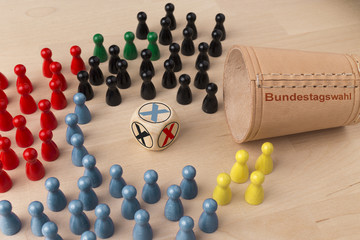Bundestagswahl, dargestellt durch Würfelbecher mit Würfel und farbige Figuren