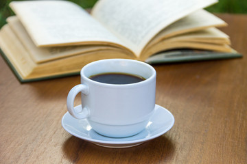 Cup of coffee and book on wooden table