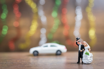 Miniature people bride and groom  on wooden floor with colorful bokeh background