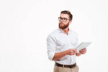 Serious young bearded man using tablet computer.