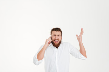 Angry young bearded emotional man talking by phone.