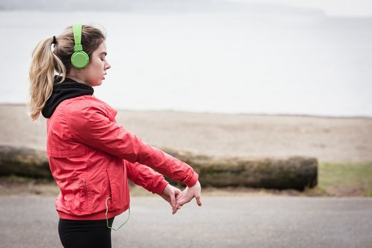 Woman exercising while listening to music at beach side