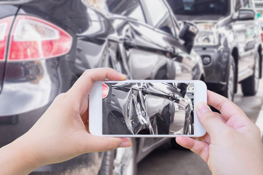 woman using mobile smart phone taking photo of the car crash damage accident