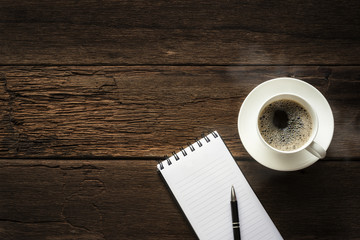 coffee cup and pen notebook on wooden table with top view