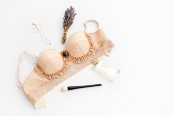 Glamorous stylish sexy lace lingerie with woman accessories on white background. Woman lace bra with perfume and necklace, flat lay, top view.Shopping and fashion concept, textile, jewelry, underwear.
