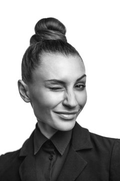 Beautiful young seductive woman in black suite coquettish winks and smiles.