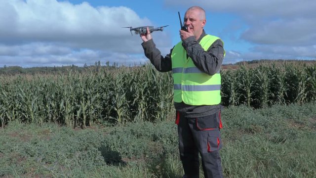 Farmer with drone and walkie talkie at corn field 