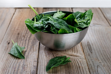 Spinach leaves in a  bowl on rustic wooden table