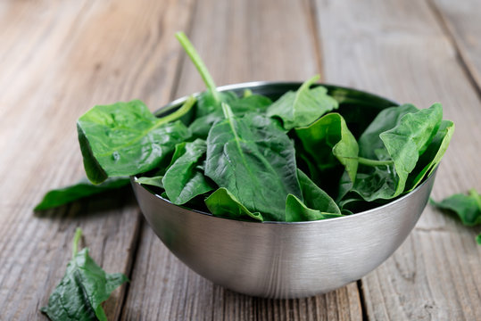 Spinach leaves in a  bowl on rustic wooden table