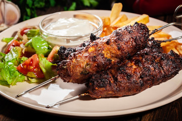Grilled shish kebab served with fried chips and salad