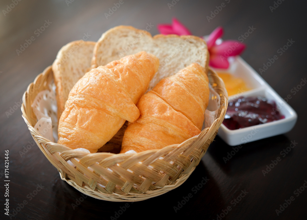 Wall mural Tasty croissants in basket on wooden background.