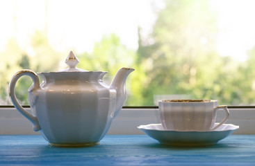 Cup and teapot in front of window.