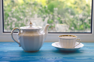 Cup and teapot in front of window.