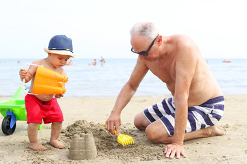Little boy and grandfather playing at the beach 