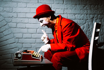 Mime in a red suit prints on a typewriter