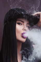 Young sexy woman is vaping. A cloud of vapor. Studio shooting.