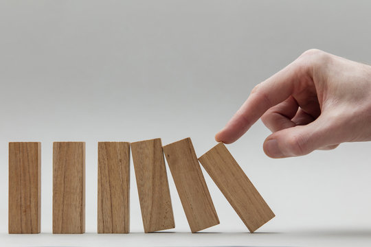 Male Hand Stopping Wooden Blocks Falling Over