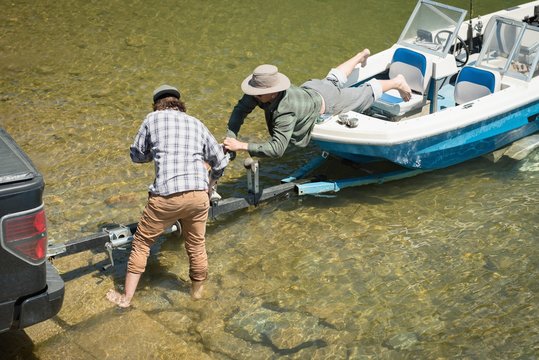 Friends attaching boat trailer to vehicle