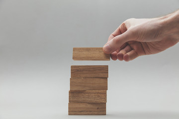 Male hand stacking wooden blocks. Business development and growth concept