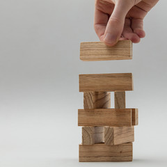Male hand stacking wooden blocks. Business development and growth concept