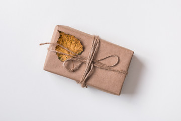 Autumn background: handmade gift in craft paper with autumn yellow leaf of white. Top view. Flat lay.