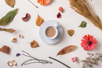 Autumn background: fallen leaves, dry petals, dried flowers and dry plants simple rustic branches and wheat bunch, cup of coffee in center. Top view. Flat lay.
