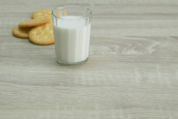 MILK AND CRACKERS
A glass of milk with pile of crackers on the wood top table. 