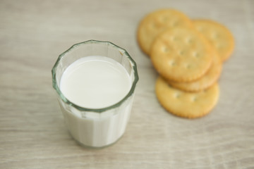 MILK AND CRACKERS
A glass of milk with pile of crackers on the wood top table. 