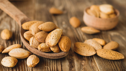 Raw almond in wooden spoon with soft focus on the old rustic table background