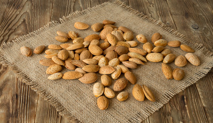 Raw almond over burlap on the old rustic table background