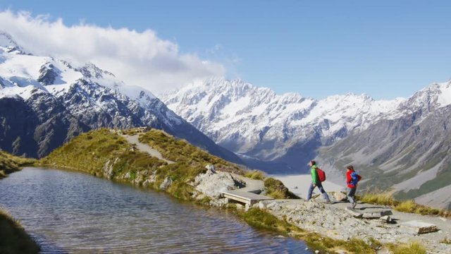 Hiking travel nature hikers in New Zealand mountains. Couple people walking on Sealy Tarns hike trail route with Mount Cook landscape, famous tourist attraction.