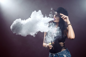 Young sexy woman is vaping. A cloud of vapor. Studio shooting.