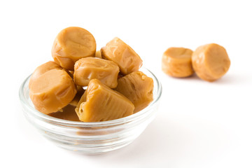 Toffee caramel candies in a crystal bowl isolated on white background. 
