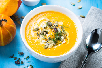 Pumpkin and carrot cream soup on blue.