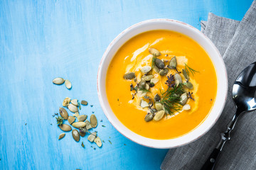 Pumpkin and carrot cream soup on blue.