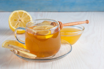 A glass cup of green natural tea with ginger, lemon, mint and honey on wooden rustic background. Healthy drink.