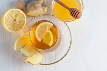 A glass cup of green natural tea with ginger, lemon, mint and honey on wooden rustic background....