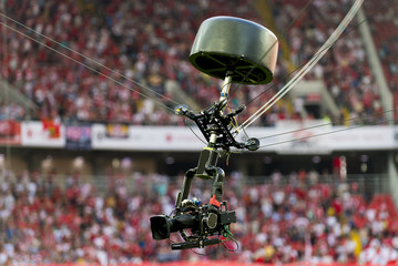 A television camera hangs on cables for football or a concert