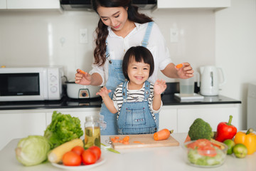 Mother with her daughter in the kitchen cooking together
